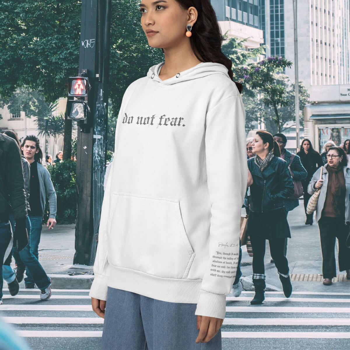 Woman in white Christian hoodie with "do not fear" text in urban city setting.