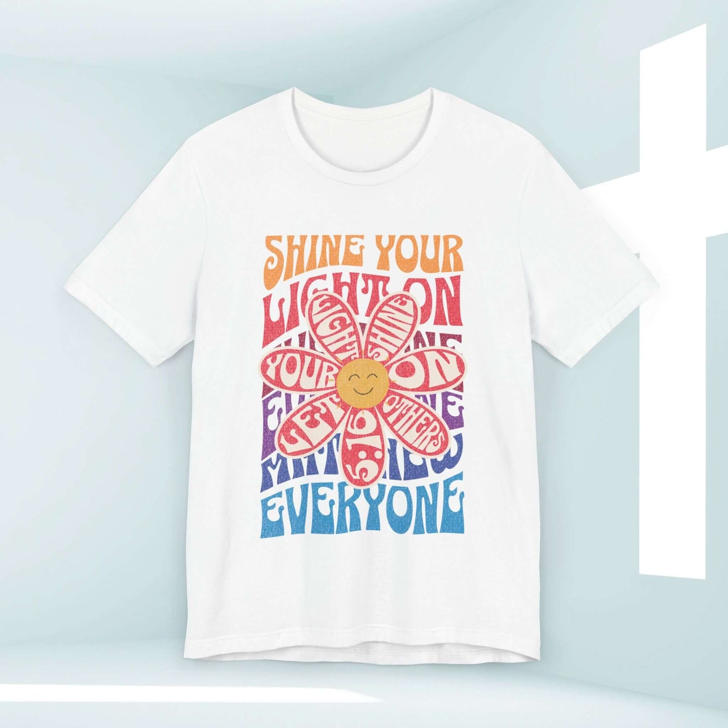 Shine Your Light Christian t-shirt with a colorful retro design featuring a flower and a positive message on soft white cotton fabric.