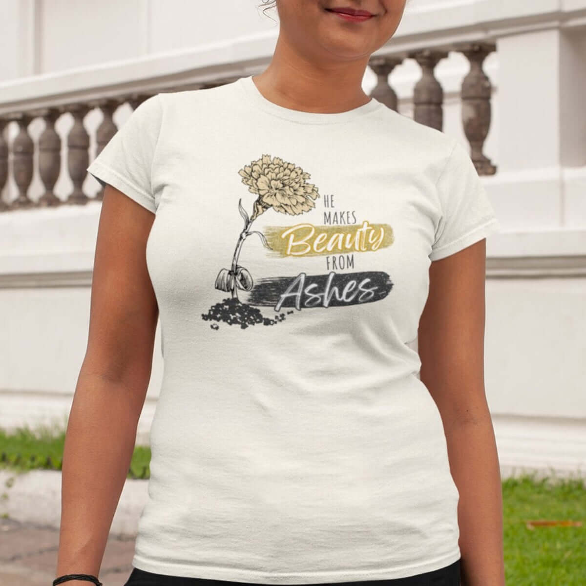 Woman wearing He Makes Beauty From Ashes Christian T-Shirt with faith-based message and floral graphic, inspirational Christian apparel.