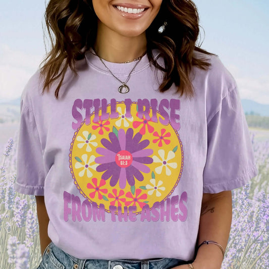 Woman wearing a purple "Still I Rise From The Ashes" Christian floral t-shirt standing in a field of flowers.