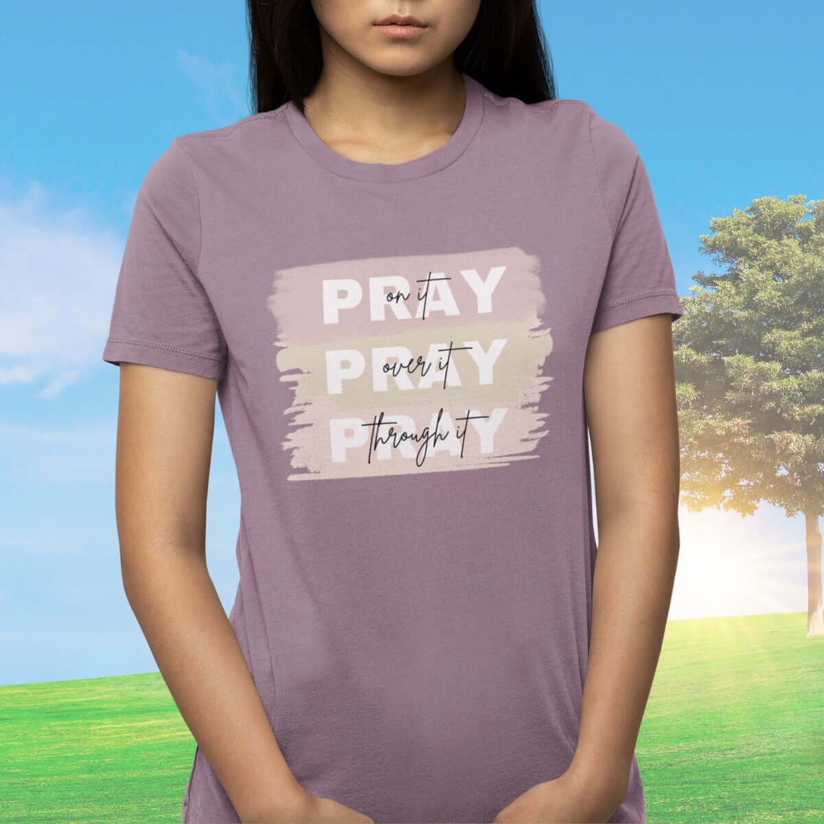 Woman wearing a purple Christian tee with "Pray On It, Pray Over It, Pray Through It" design, inspirational faith-based apparel.