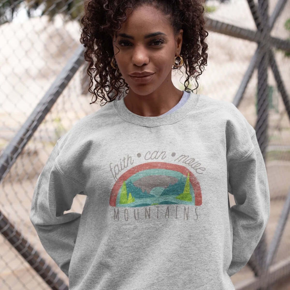 Woman wearing a Christian crewneck sweatshirt with Bible verse "Faith Can Move Mountains," showcasing faith apparel and inspirational Christian clothing.