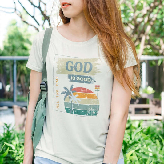 Woman wearing a 'God Is Good All The Time' Christian t-shirt in a summer setting.