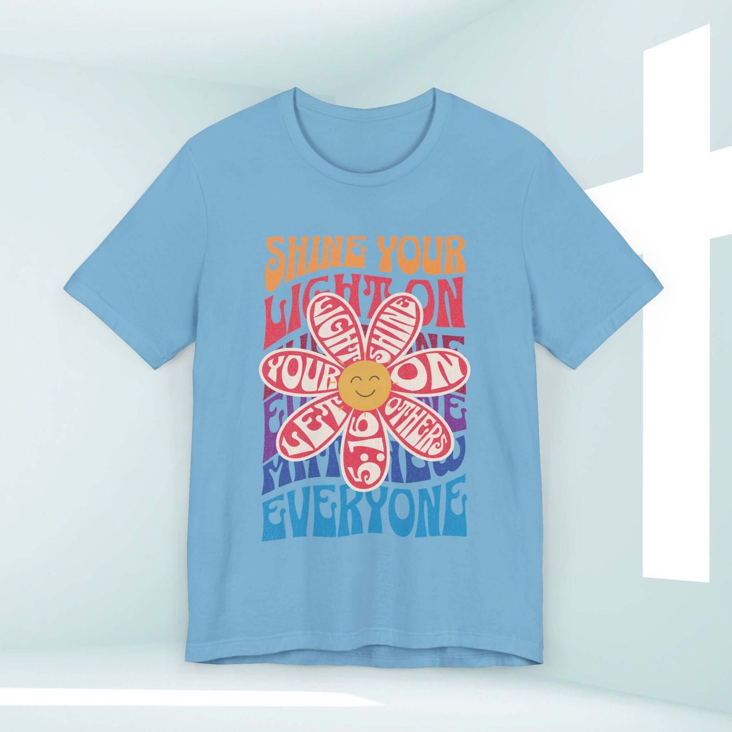 Shine Your Light Christian shirt with retro-style design, inspirational faith-based graphic t-shirt hanging against a light background