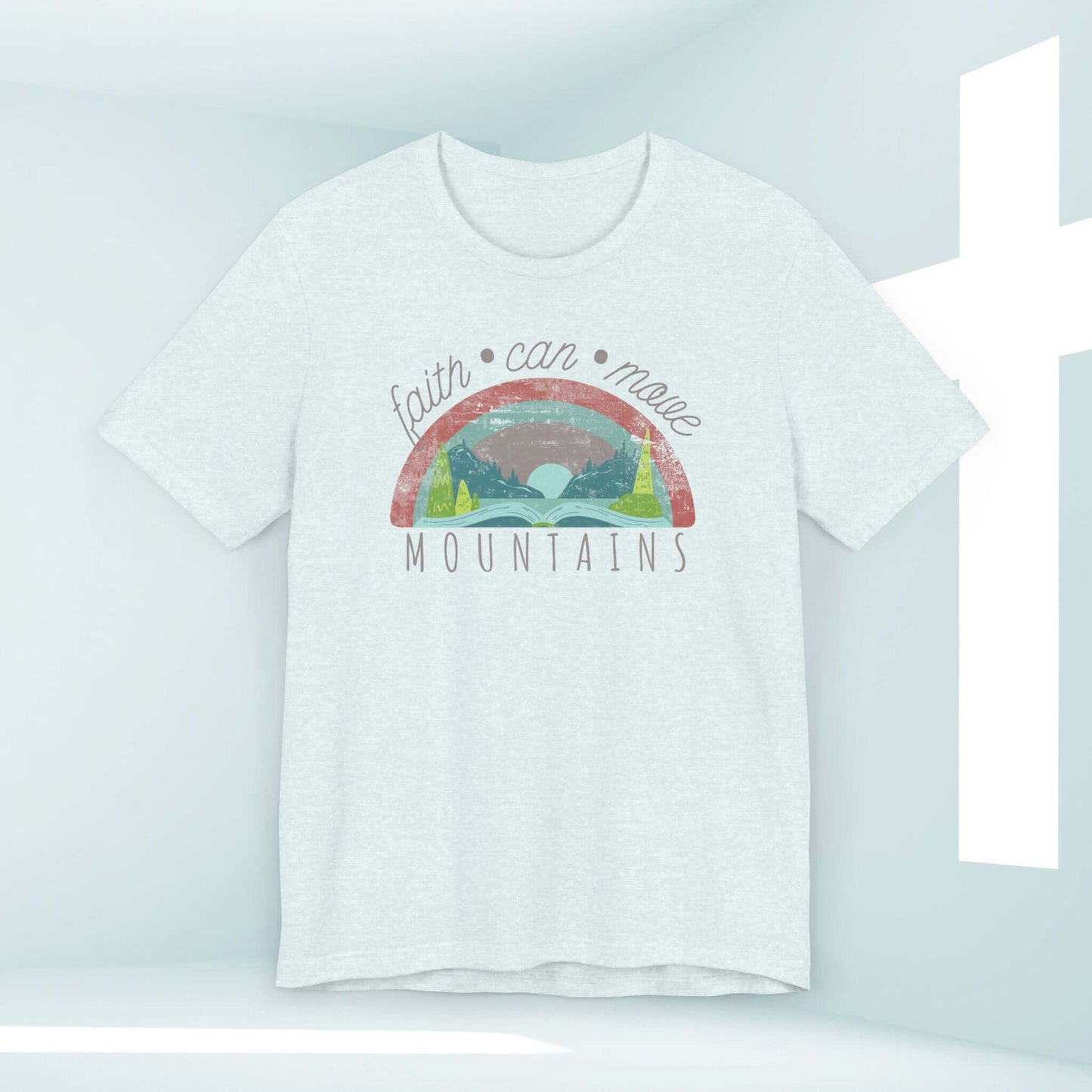 "Faith Can Move Mountains Women's Christian Rainbow T-Shirt featuring an inspirational design in a light room with a cross symbol"