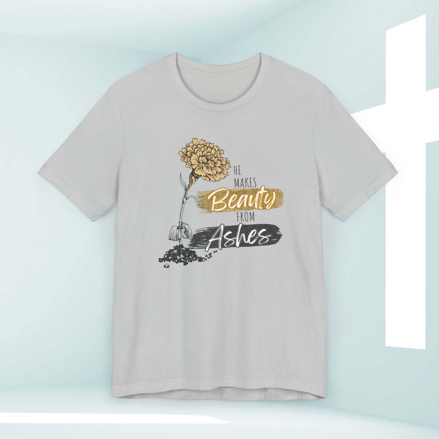 He Makes Beauty From Ashes women's Christian T-shirt with Bible verse and floral design against a light background with a cross.