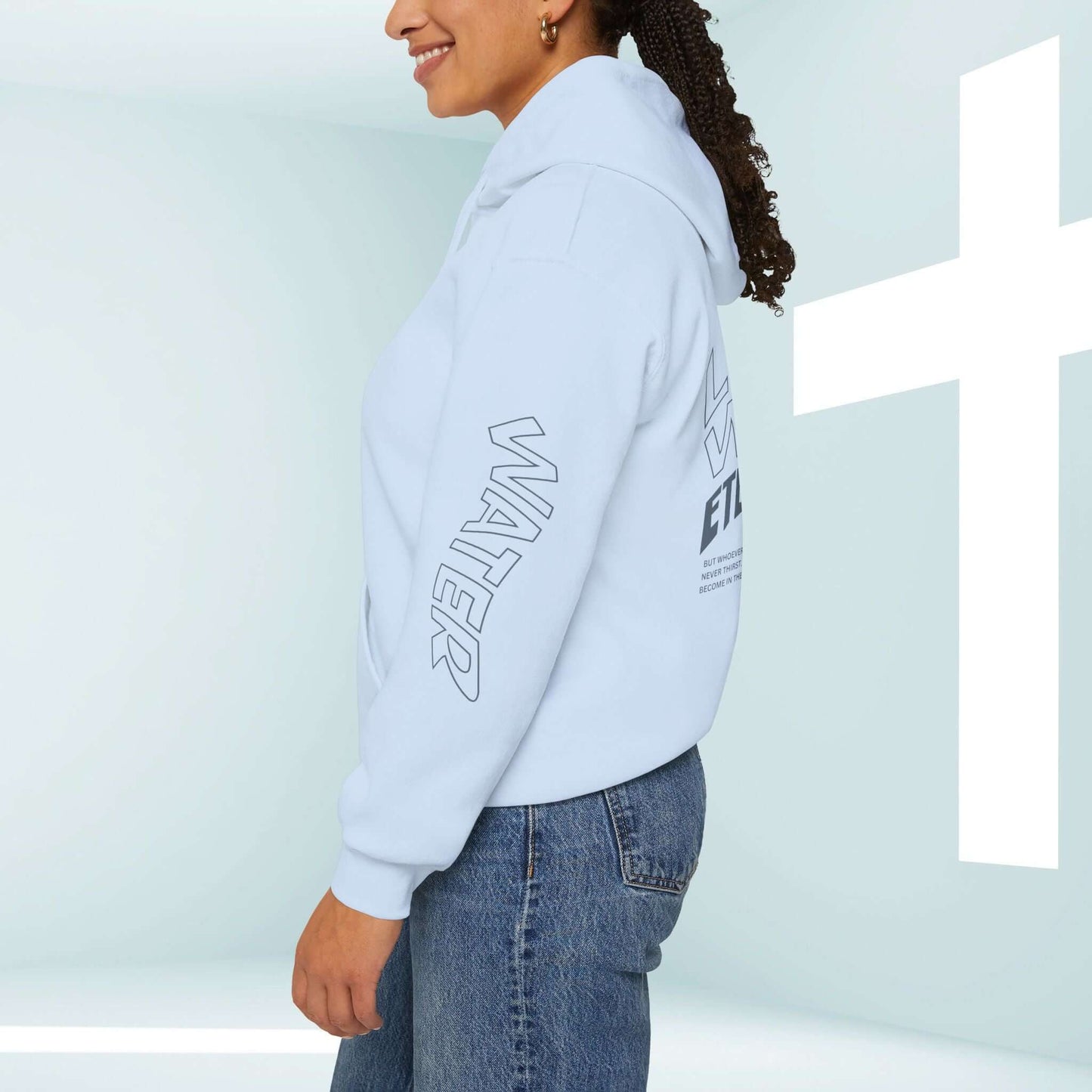 Woman wearing light blue "Living Water Eternal Life" Christian hoodie with cross in background, side view of unisex faith-based hooded sweatshirt