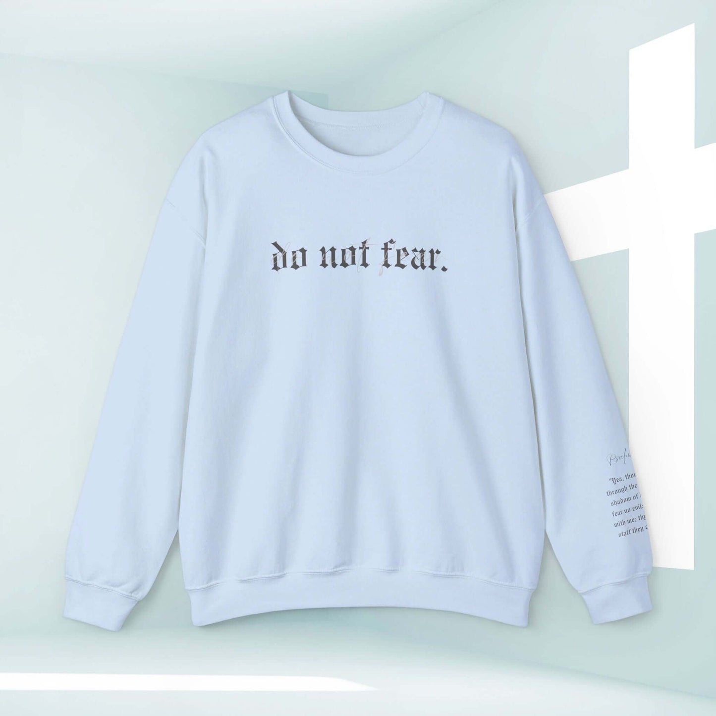 Light blue Christian sweatshirt with "do not fear" text, displayed next to a white cross background