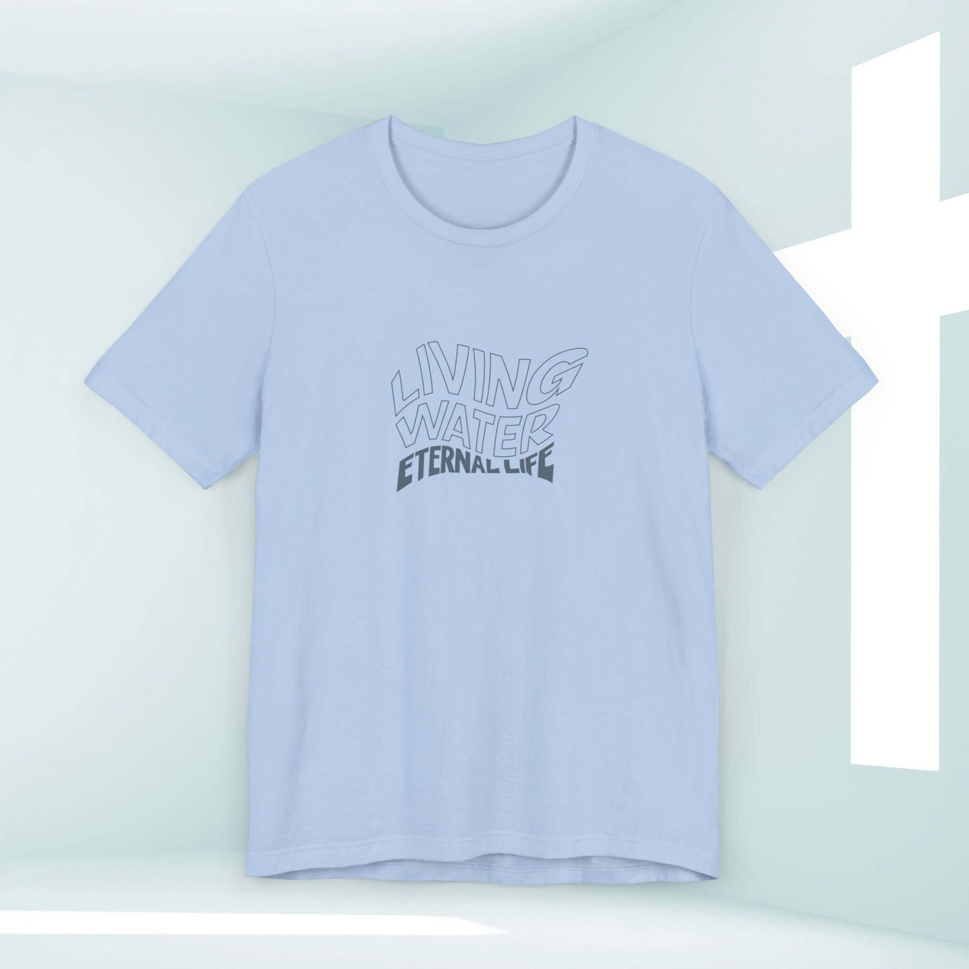 Light blue Living Water Eternal Life T-Shirt with faith-based graphic in a minimalist room with a white cross.