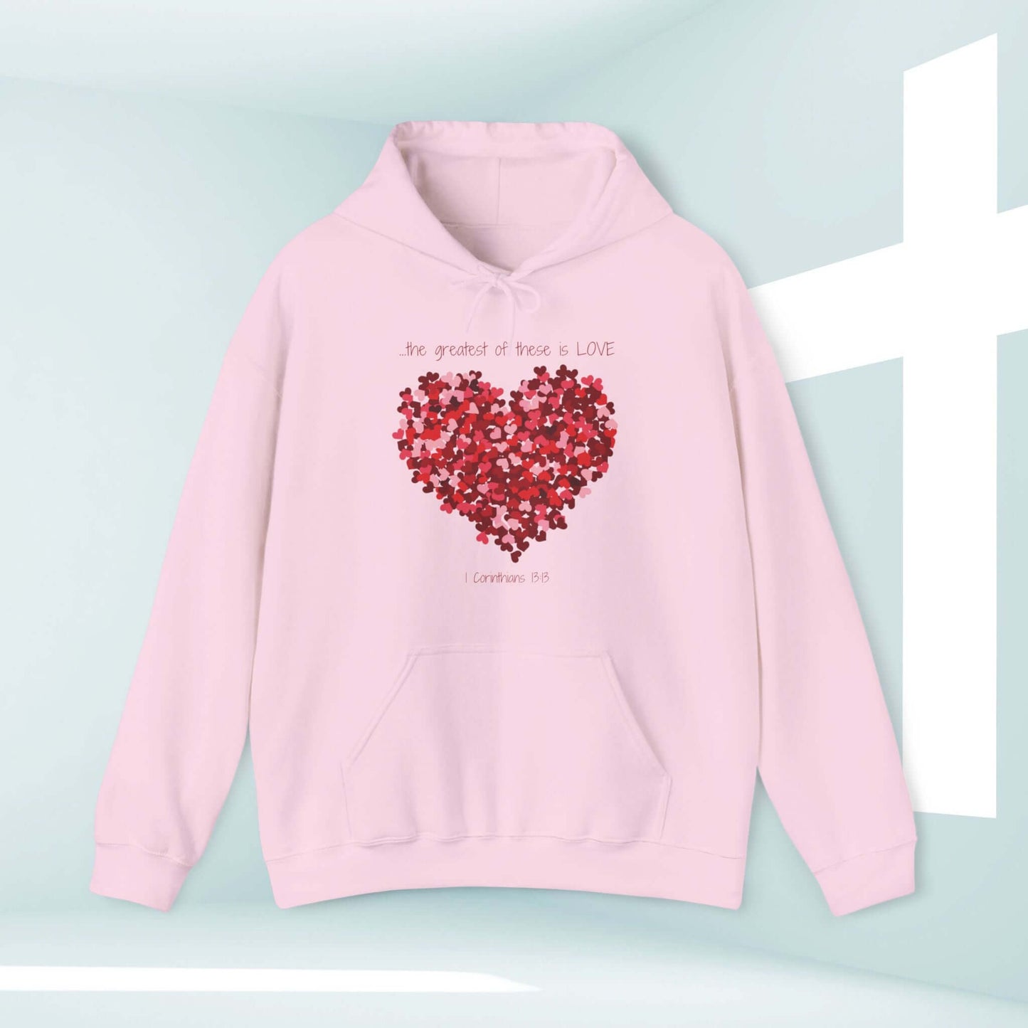 Pink Christian Valentine's Day hoodie with a heart design and "The Greatest Of These Is Love" Bible verse, perfect for anniversaries and weddings.