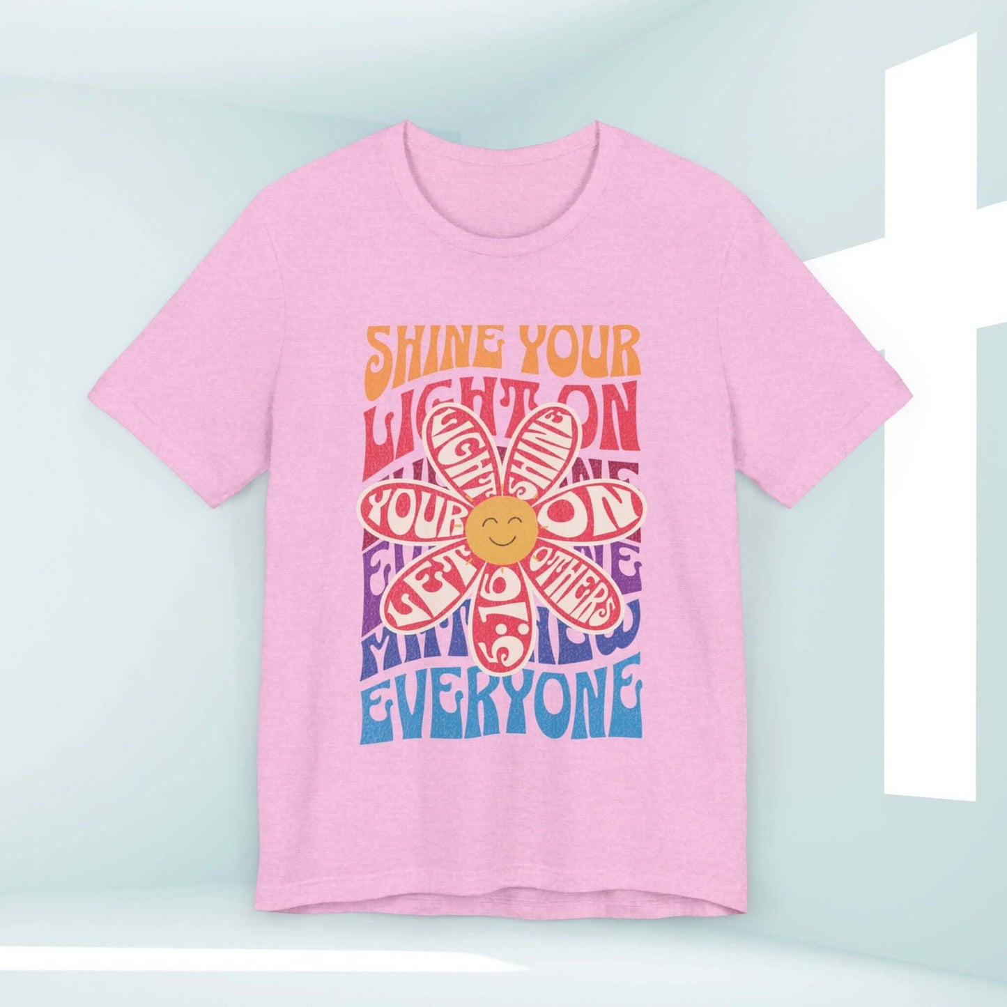 Shine Your Light Christian shirt in pink with inspirational graphic design featuring a retro daisy and message to uplift and spread love.