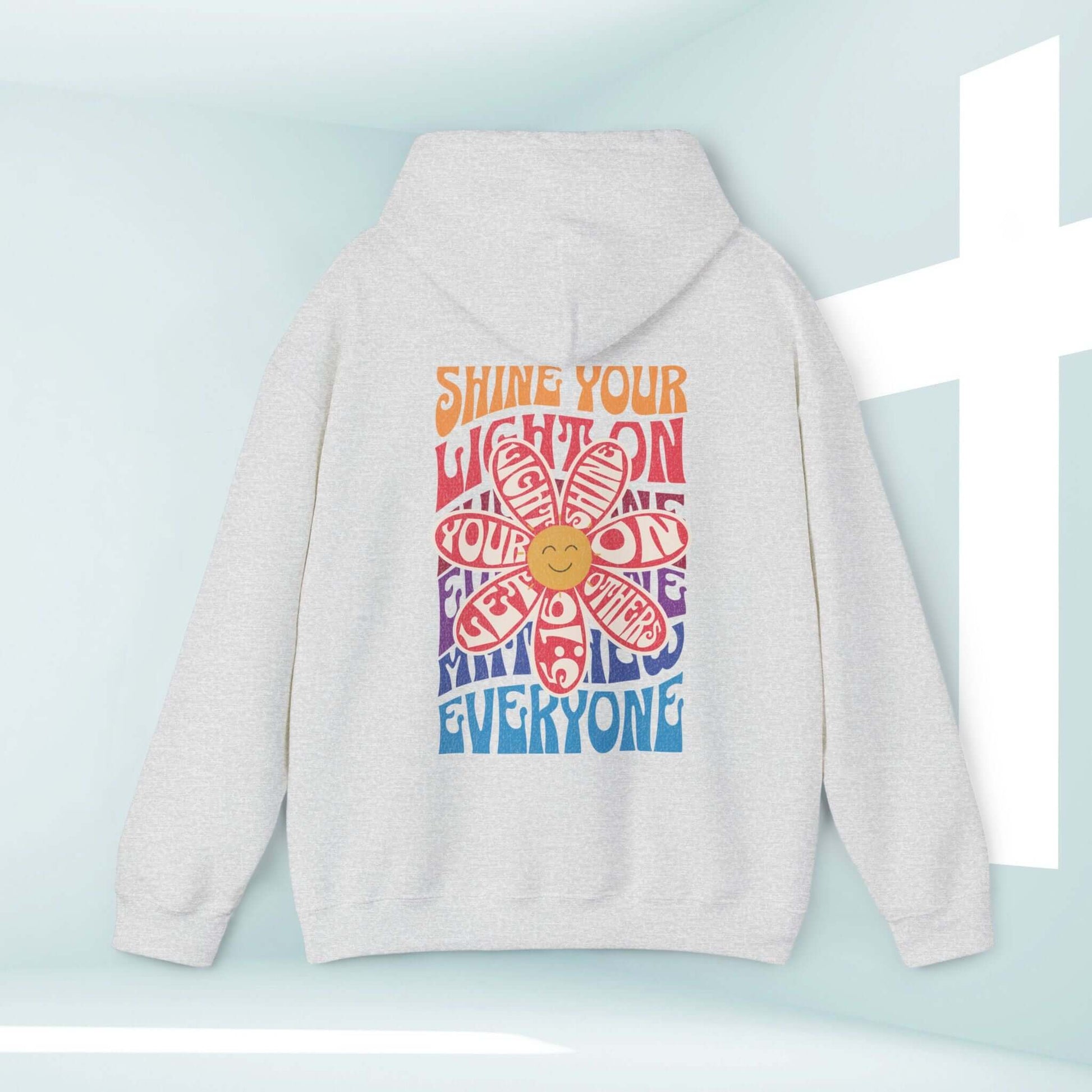 Christian hoodie with "Shine Your Light" Bible verse, boho floral design, and smiley face. Faith-based inspirational pullover sweatshirt.