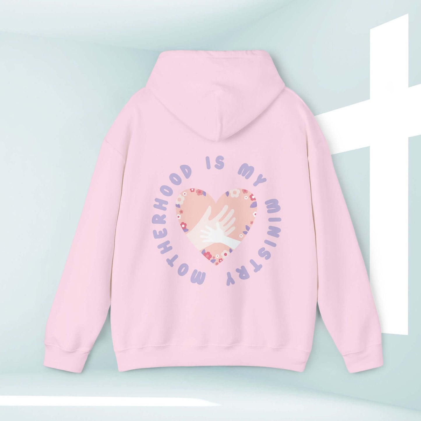 Pink Christian hoodie with "Motherhood Is My Ministry" printed on the back, featuring a heart and hands design, perfect gift for new moms and homeschoolers.