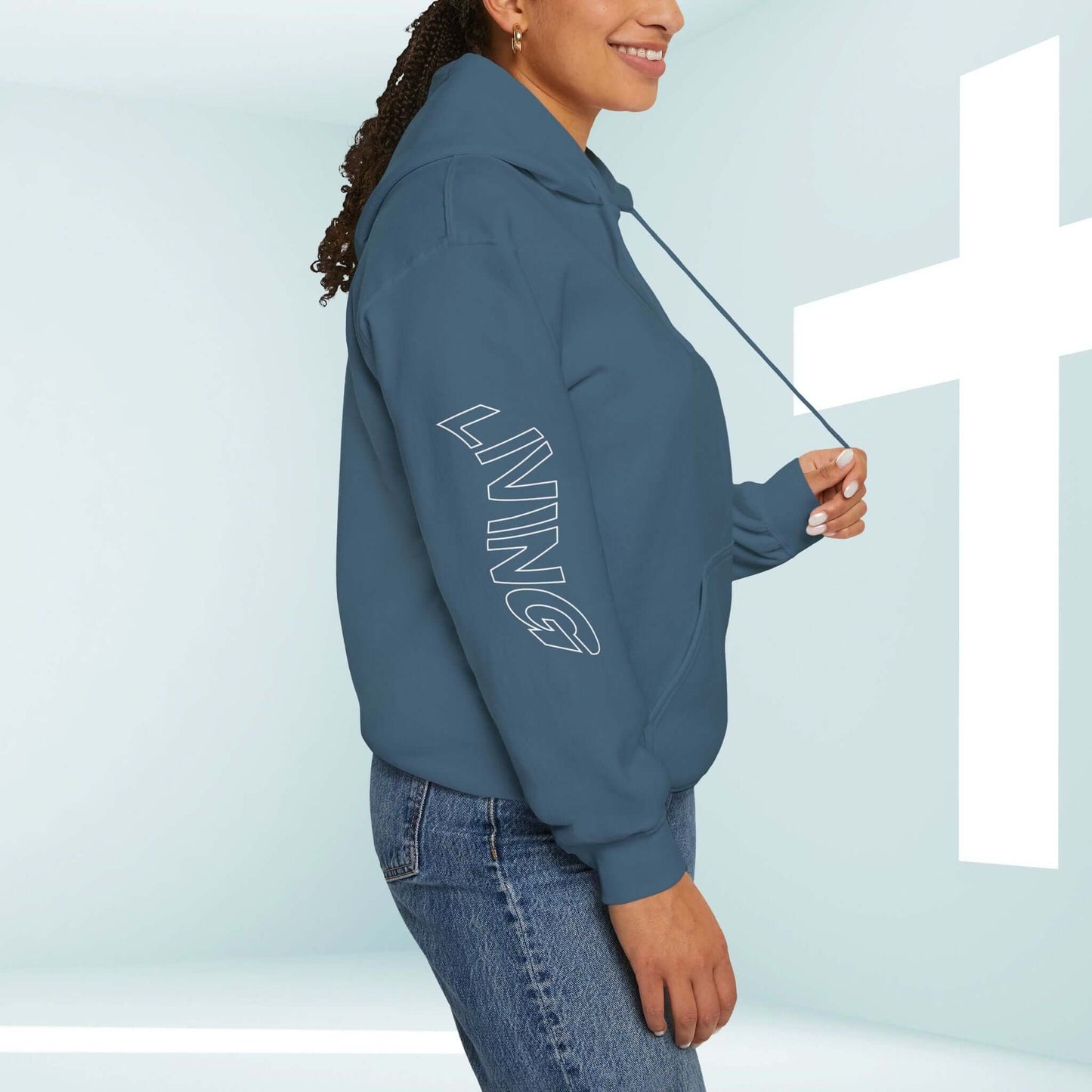 Woman wearing a Living Water Eternal Life Christian hoodie with Living Water graphics on sleeves in front of a cross in a lighted room.