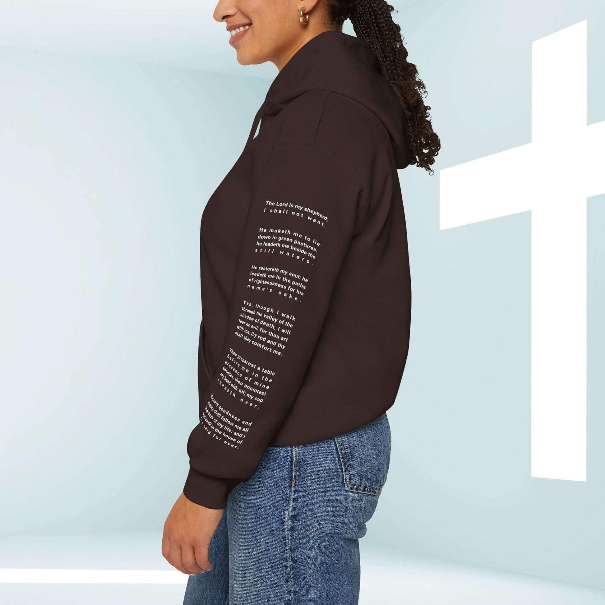 Woman wearing a black Fearless Psalm 23 Christian hoodie with Bible verse graphics on left sleeve, displaying faith-based inspirational message.