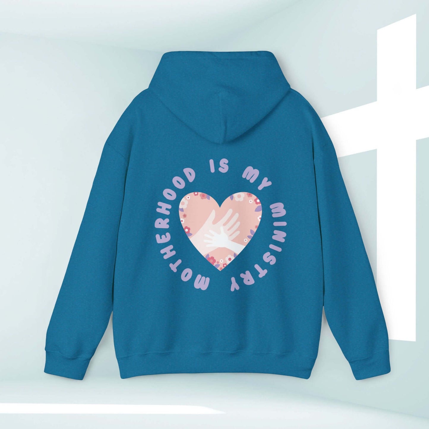 Motherhood Is My Ministry Christian hoodie in blue, featuring a heart graphic with hands, perfect for homeschooling moms and inspirational gifts.