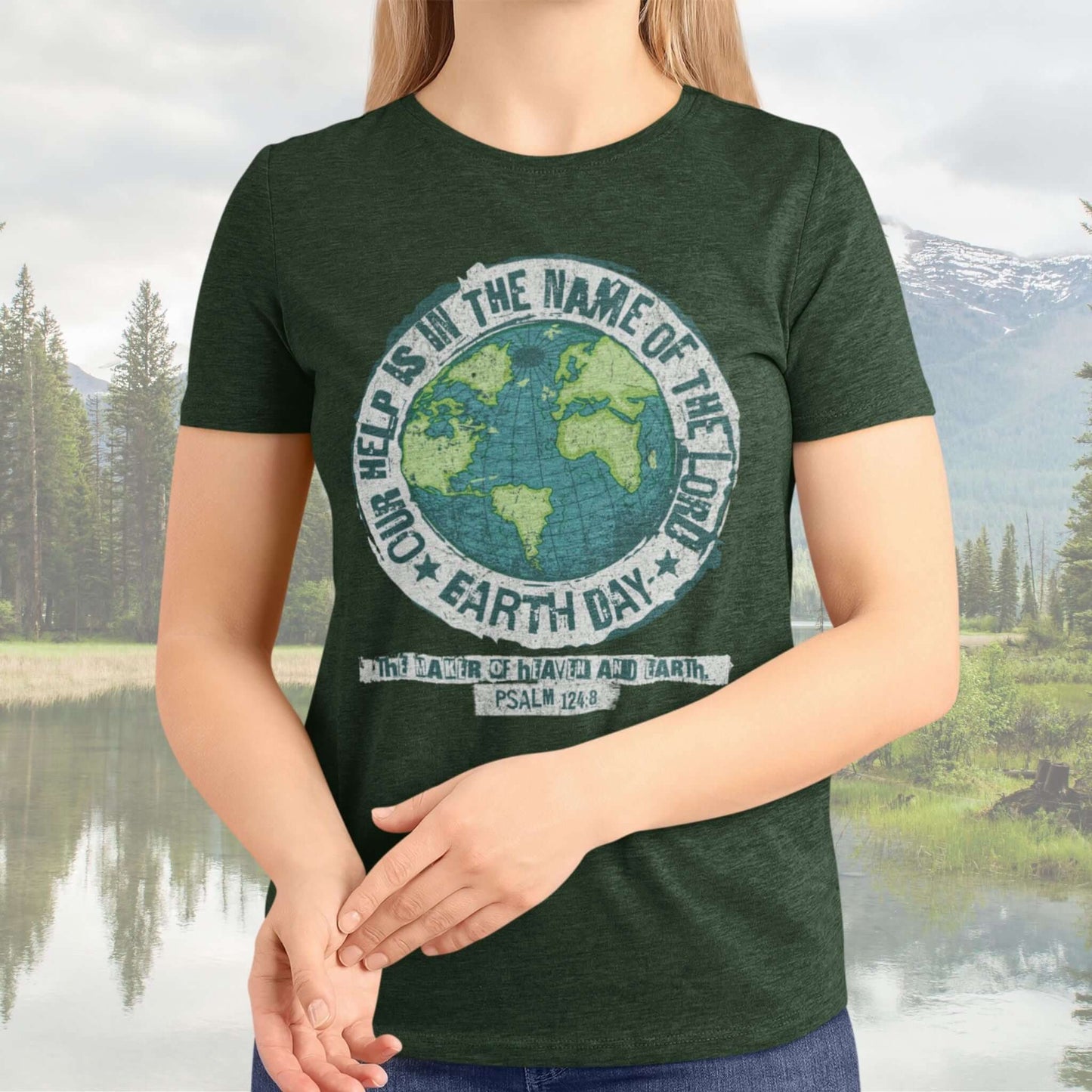 Woman wearing a Christian Earth Day shirt with a globe graphic and verse, surrounded by nature.