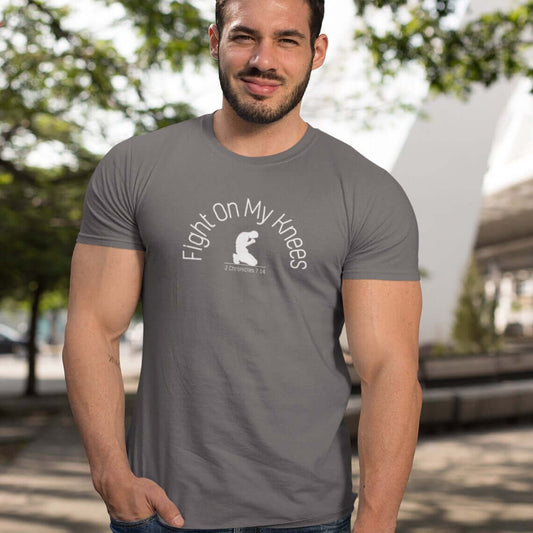 Fight On My Knees men's Christian T-shirt, faith-based graphic inspirational shirt, grey, outdoor setting, worn by a man