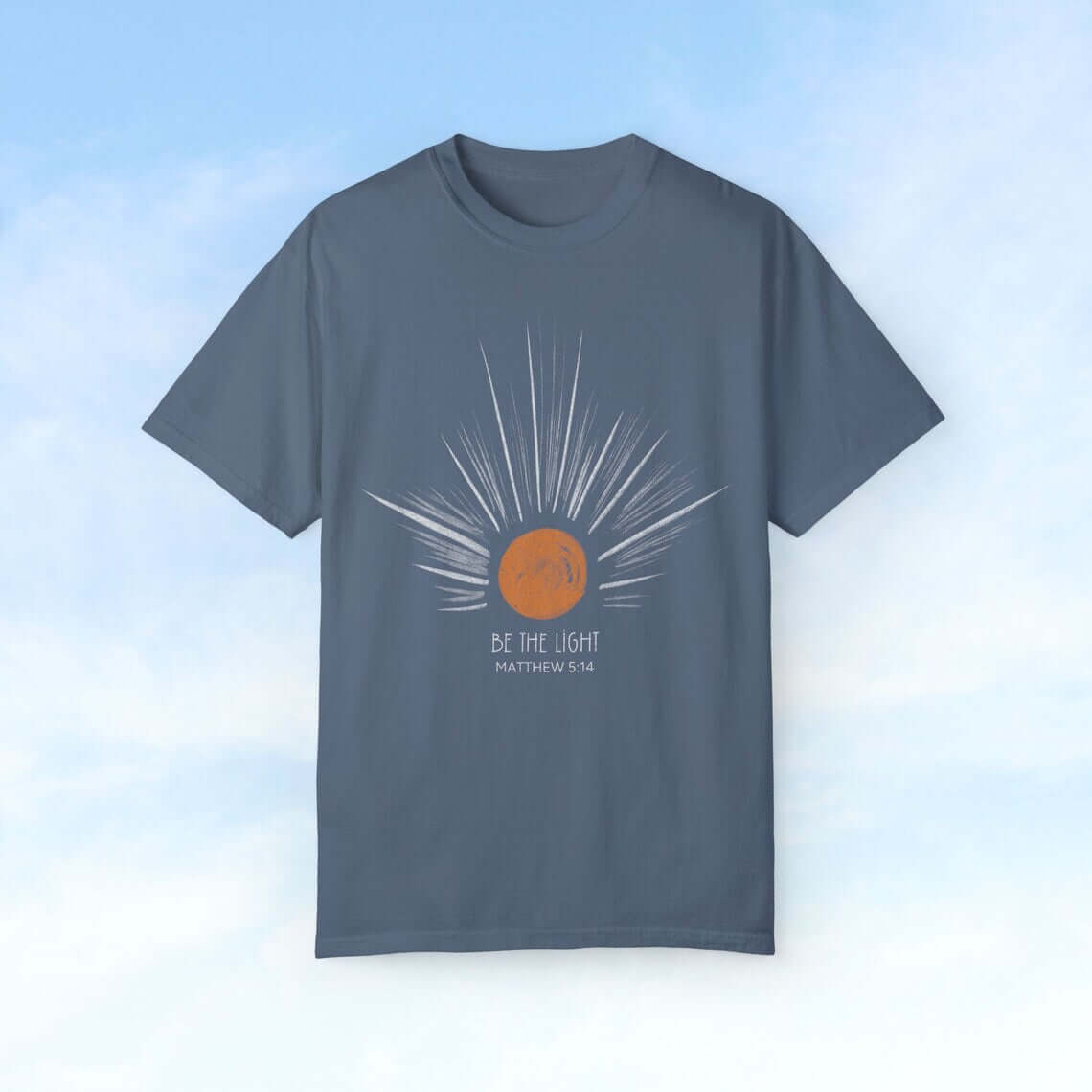 Be The Light Sunburst Christian T-shirt with Matthew 5:14 Bible verse, featuring celestial sun rays design on blue background. Perfect Christian gift for mom.